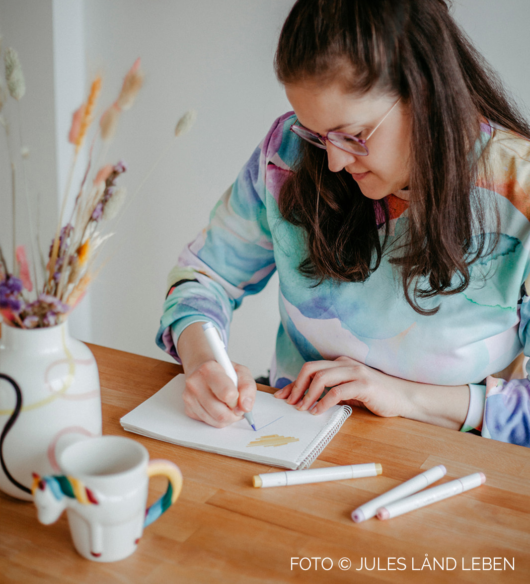 Grafikdesignerin Eva Lisette Zahneißen beim Zeichnen am Tisch